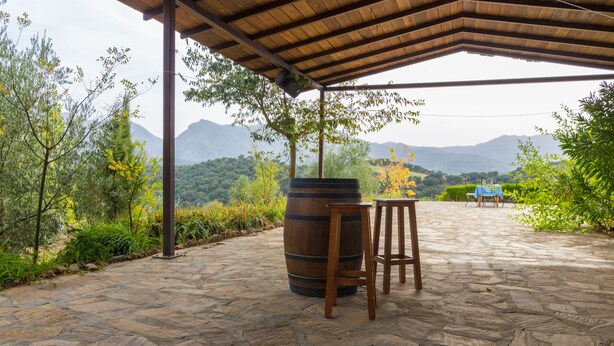 An outdoor patio with stone flooring, a wooden barrel, and a table with chairs. - Cortijo Moyano (Alhama de Granada)