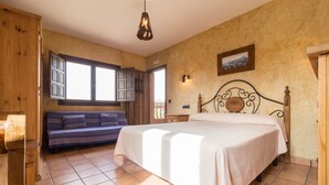 A bedroom with a bed, a sofa, a window, and a door. - Cortijo Moyano (Alhama de Granada)