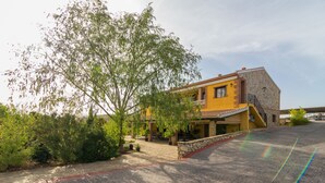 A yellow building with a stone facade, a staircase, and a paved driveway. - Cortijo Moyano (Alhama de Granada)