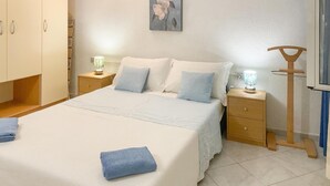 Ein Schlafzimmer mit einem Bett, zwei Nachttischen, einer Lampe, einem Gemälde und einem Holzstuhl.