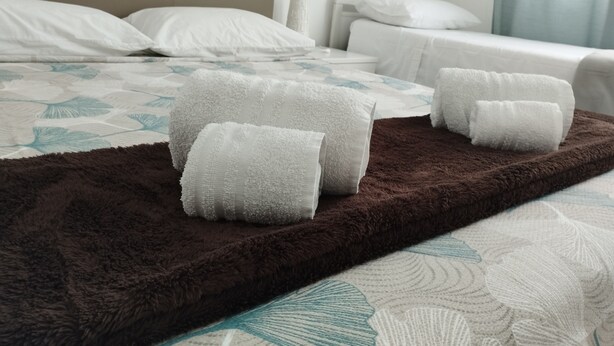 A hotel room with a bed, pillows, a blanket, and a bedside table. - Thomas'home (Comiso)