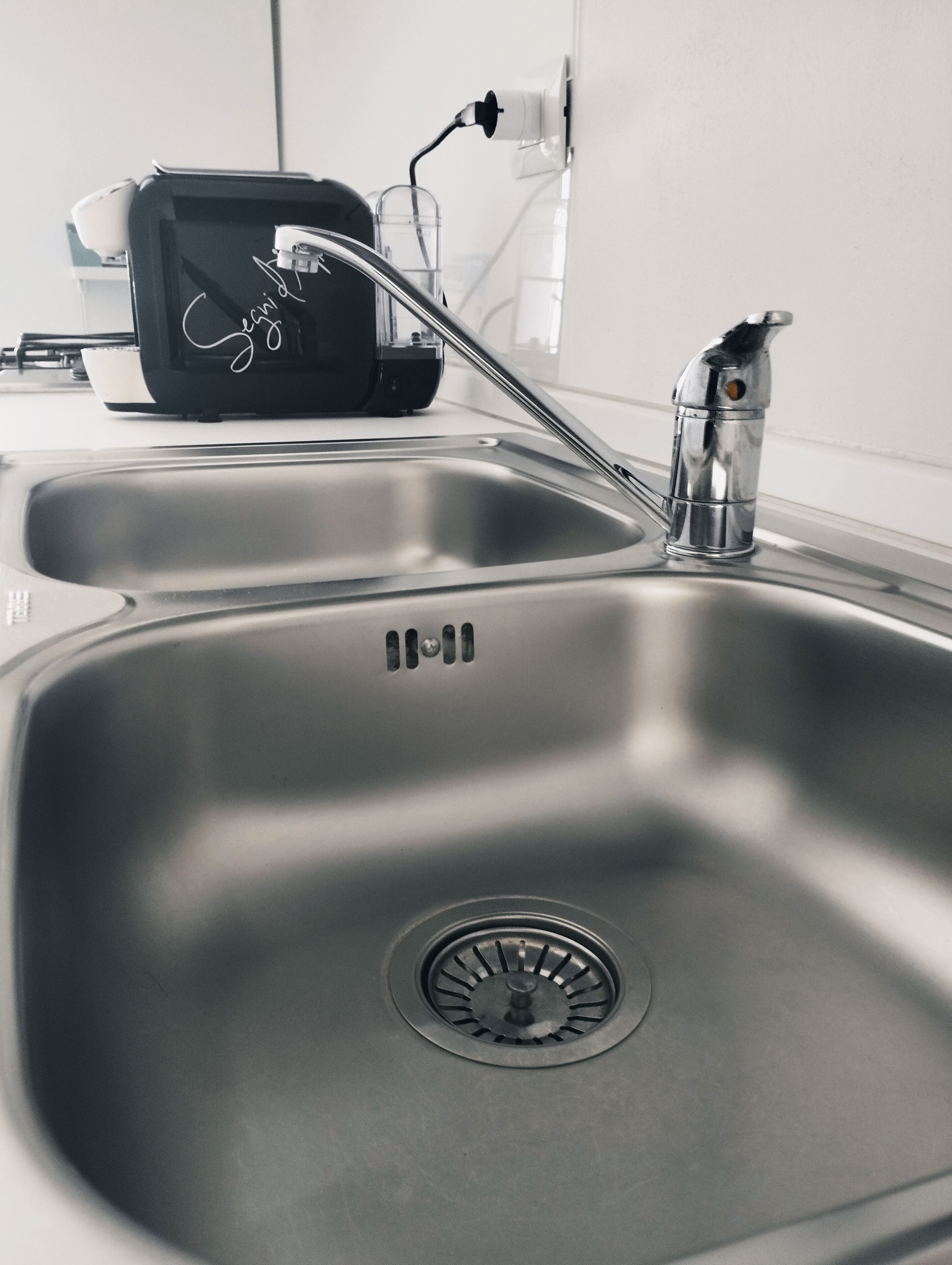 Un lavamanos de acero inoxidable con un grifo moderno e instalación de desagüe integrada.