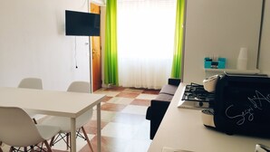 A compact kitchen with a dining area, a gas stove, and a flat-screen TV mounted on the wall. - Thomas'home (Comiso)