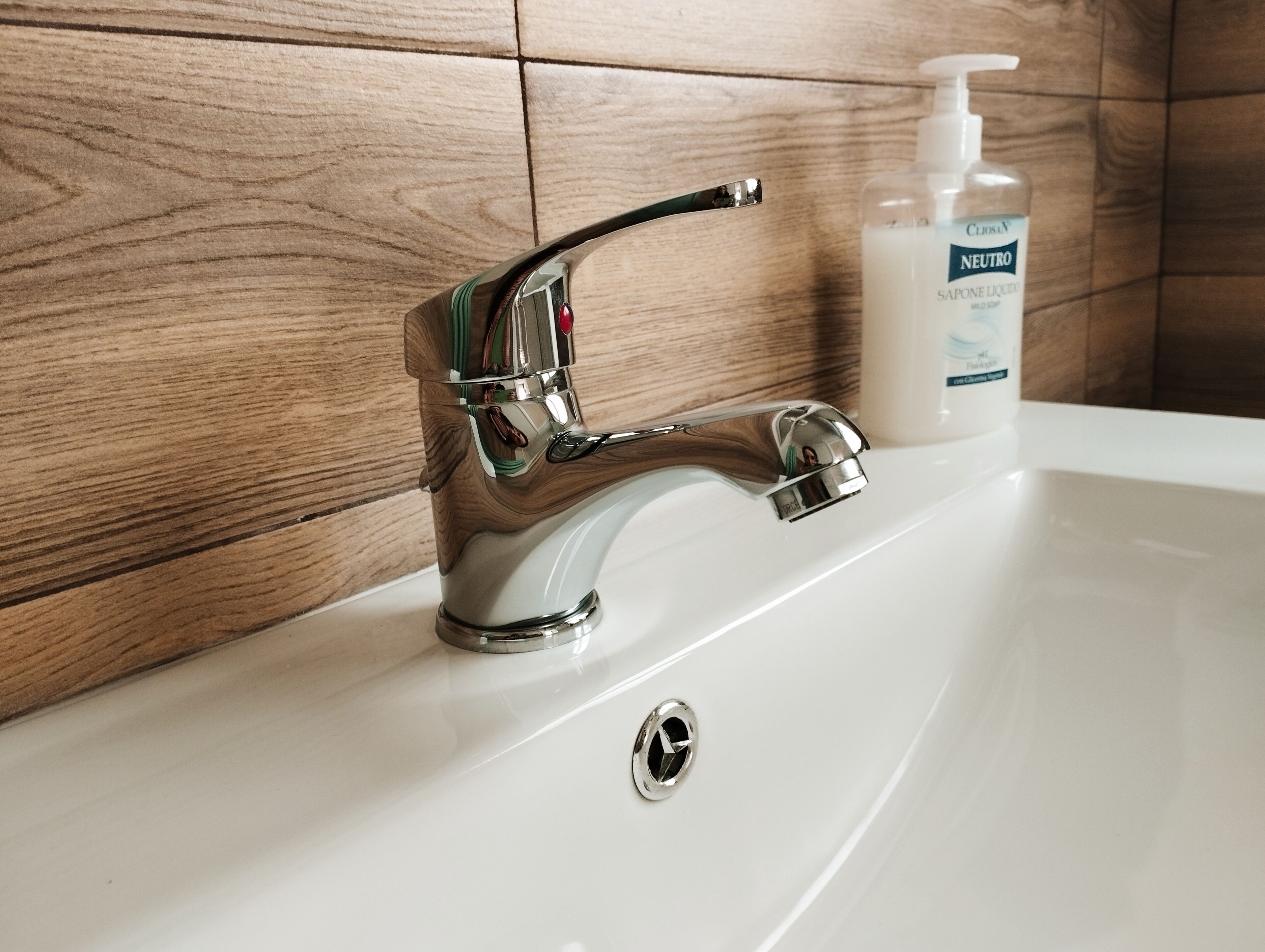 Ein Waschbecken mit chromfarbenem Wasserhahn und Seifenspender.