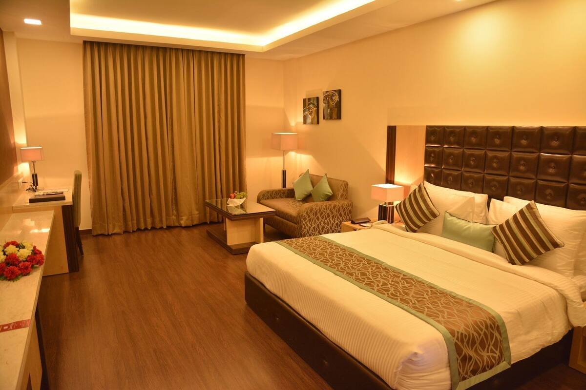 A hotel room with a large bed, two bedside tables, a desk, and a chair.