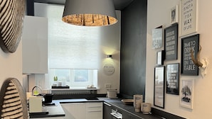 Une cuisine moderne dotée d’un îlot central, de luminaires suspendus et de divers tableaux avec des citations accrochés au mur.
