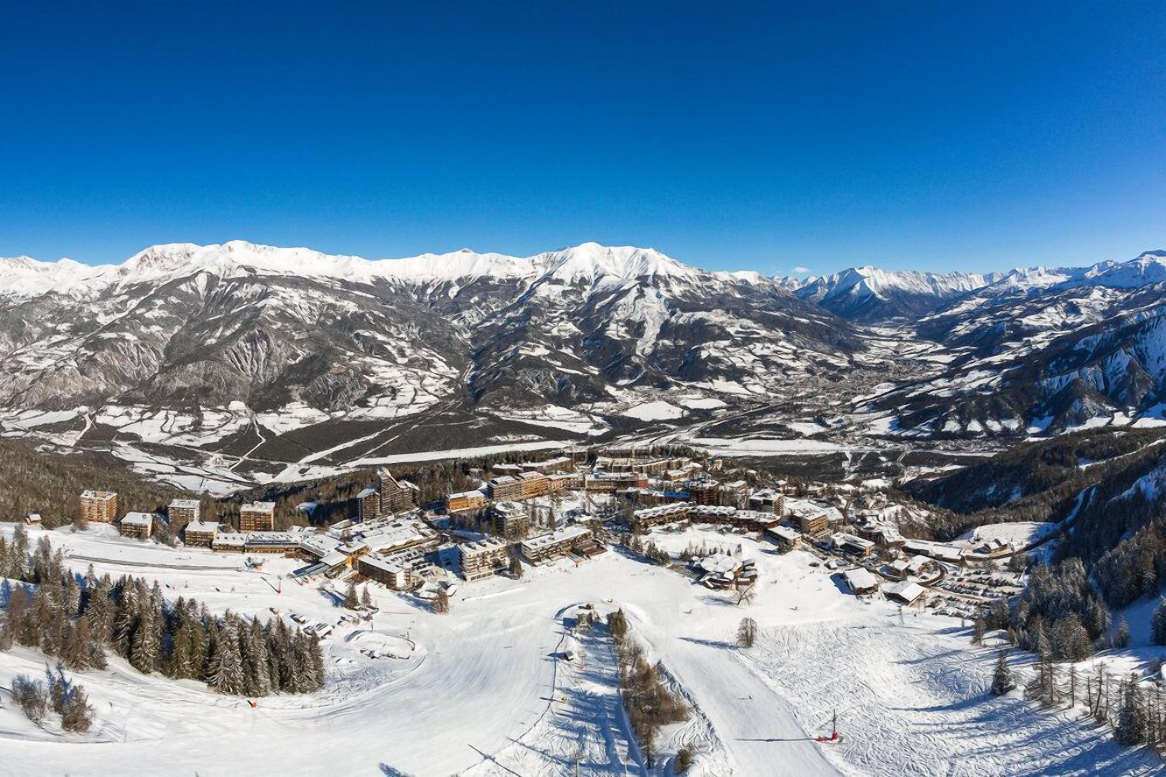 A snow-covered mountain town with buildings and ski slopes.