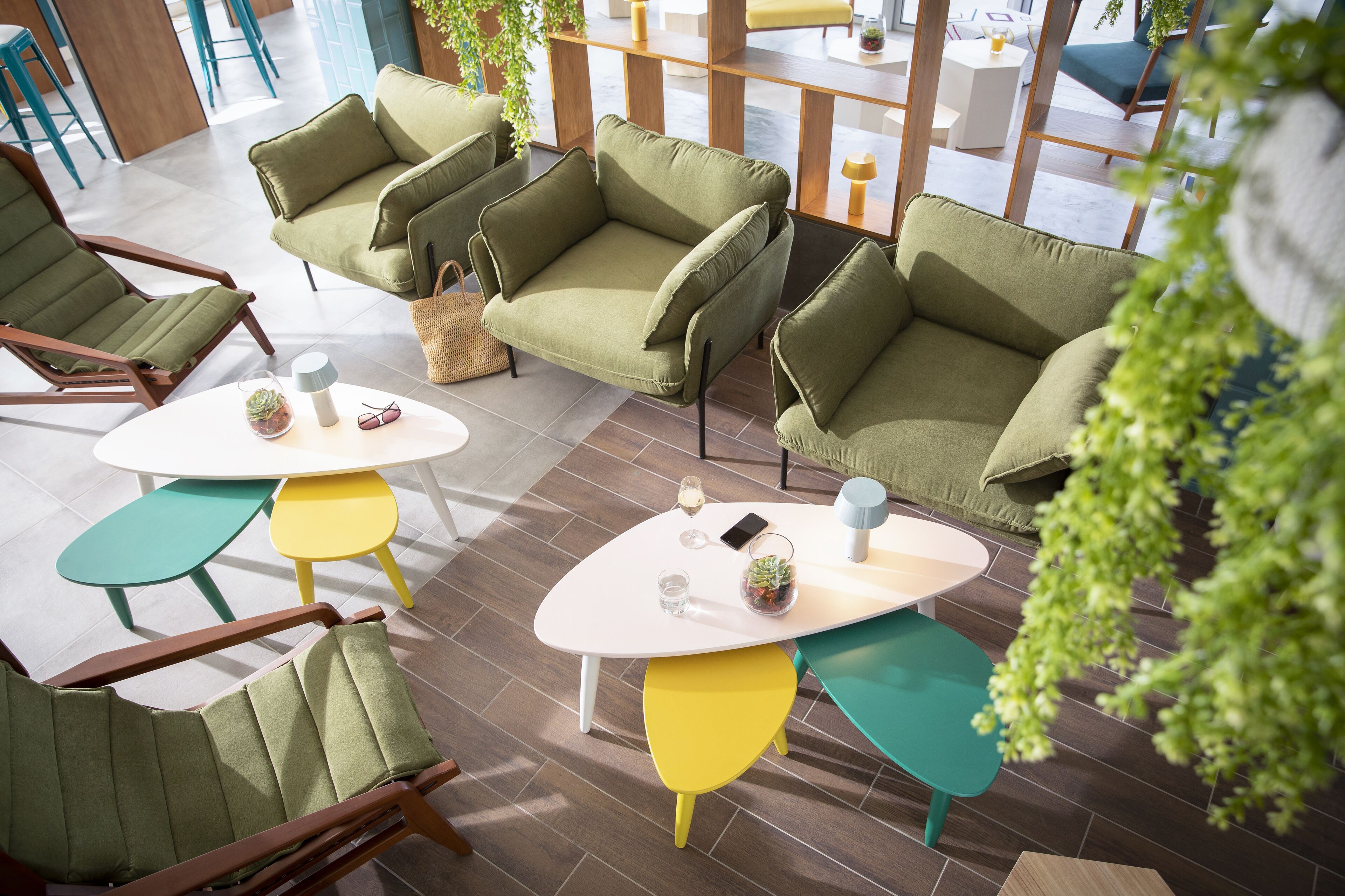 A modern indoor seating area with green sofas and yellow tables, featuring a clean, contemporary design.