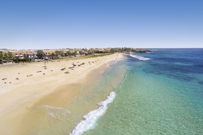 En la playa, arena blanca, sillas reclinables de playa, sombrillas