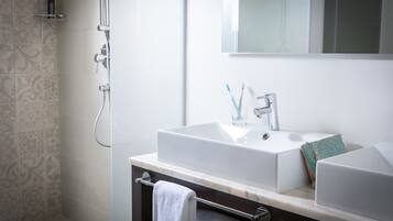 Une salle de bain moderne avec un double vasque, une douche à parois de verre et un porte-serviettes.