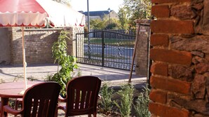 Ein Patio mit Ziegelmauern, einem Metallgitter und Gartenmöbeln.