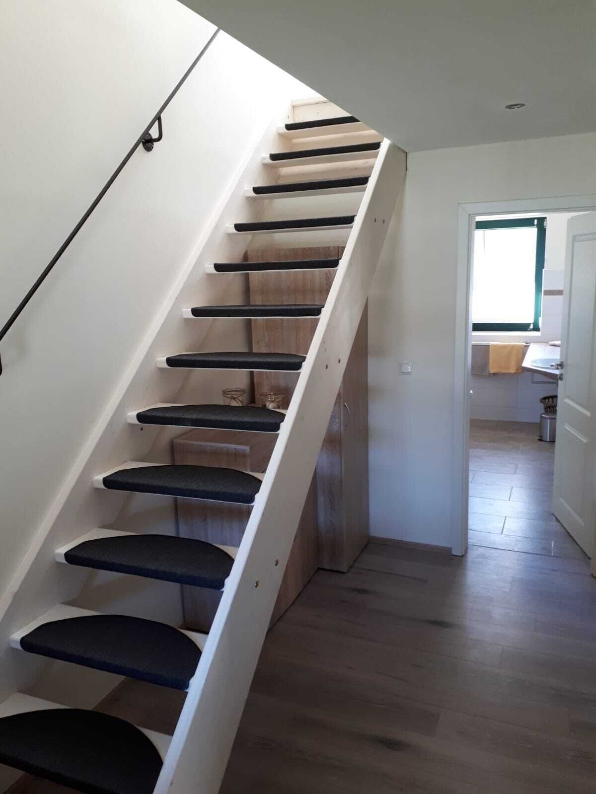 A staircase with black cushioned steps leading to a landing.