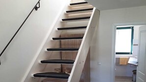 Eine Treppe mit schwarzen, gepolsterten Stufen, die zu einer Zwischenebene führen.