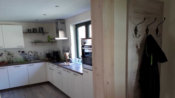Eine moderne Küche mit weißen Schränken, einer Holz Arbeitsplatte und einem Fenster, das für natürliches Licht sorgt.