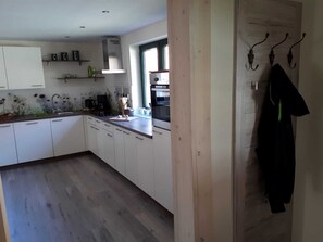 Une cuisine moderne avec des meubles blancs, un plan de travail en bois et une fenêtre qui laisse entrer la lumière naturelle.