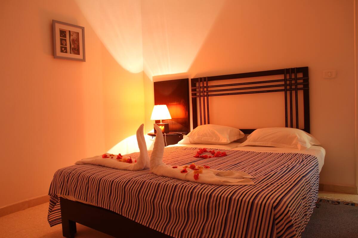 Ein Hotelzimmer mit einem Bett, einem Nachttisch, einer Lampe und einem Bild an der Wand.