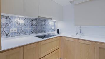 Une cuisine moderne avec un crédence à motifs, des plans de travail blancs, des armoires en bois et une cuisinière intégrée.