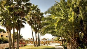 A resort with palm trees, a pool area, and a view of the sea. - Hapimag Resort Paguera (Calvia)