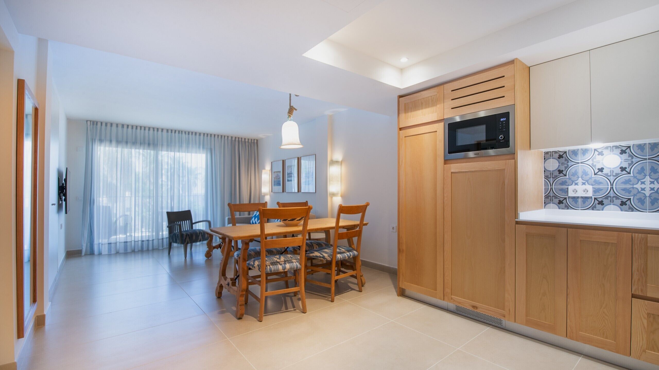 Una cocina moderna con armarios de madera, microondas integrado y salpicadero de azulejos.