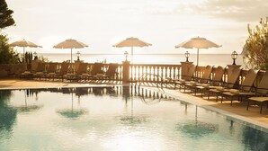 A poolside area with lounge chairs and umbrellas, overlooking the sea. - Hapimag Resort Paguera (Calvia)