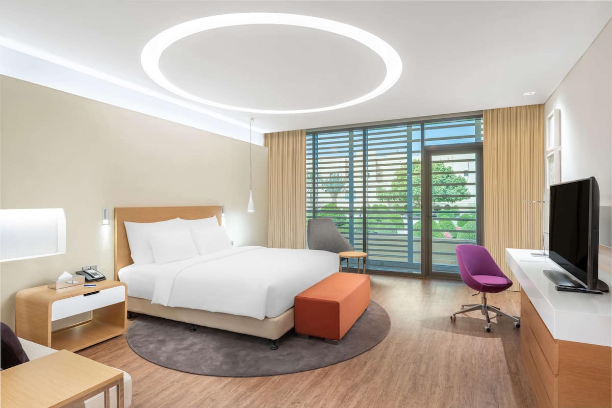 Una habitación de hotel moderna con una cama grande, un escritorio, una silla y un televisor.
