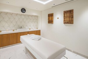 A modern bathroom with a wooden vanity, a white sink, a clock, and two decorative wall panels.