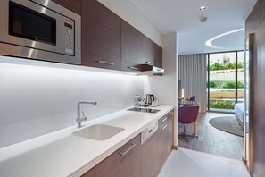 A modern kitchen with a built-in microwave, stainless steel sink, and a dining area with a table and purple chairs.