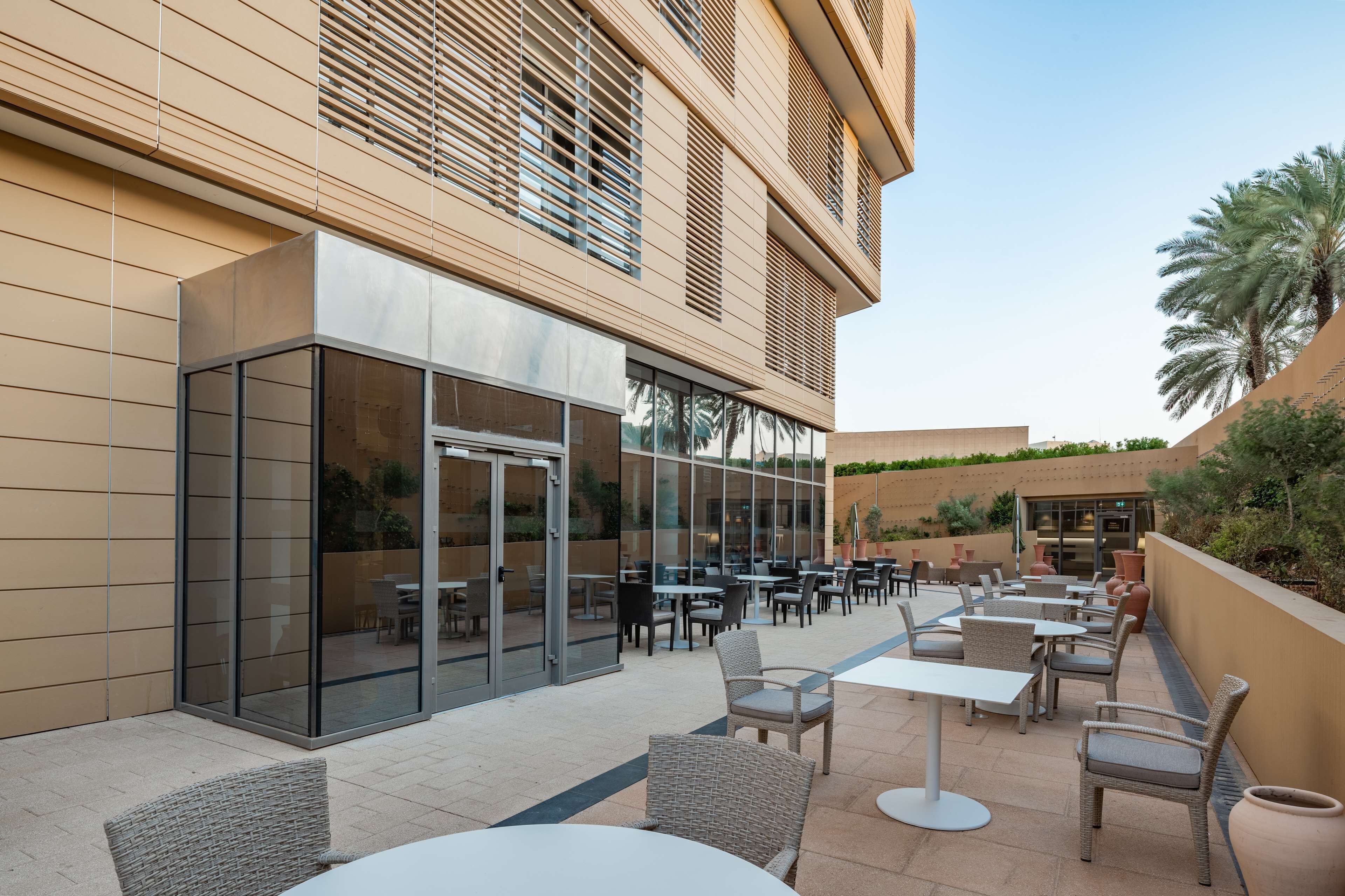 Eine moderne Außenpatio mit Glastüren, Korbmöbeln und Blick ins Innere des Gebäudes.