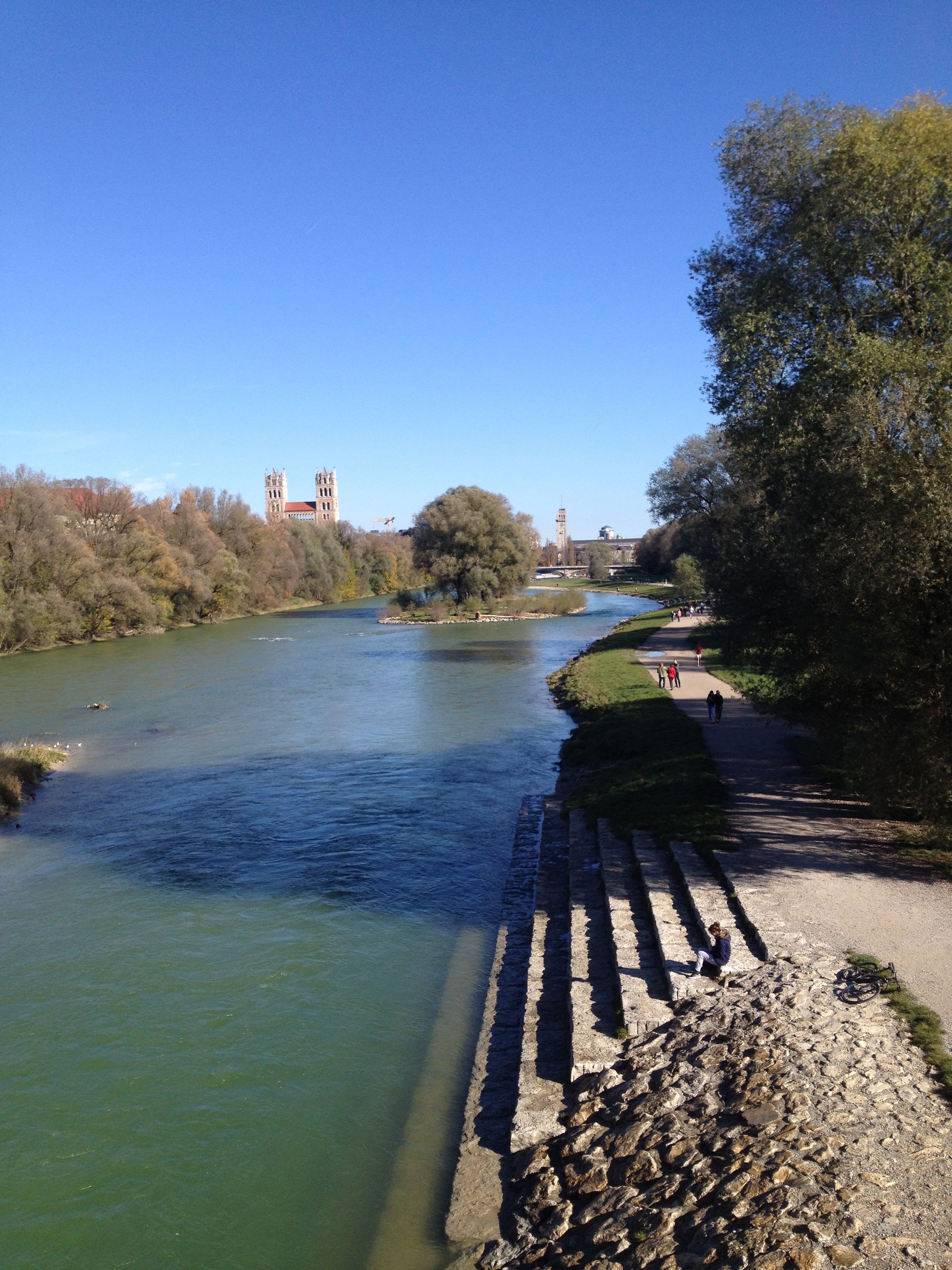 A river with a stone embankment and a bridge in the background.