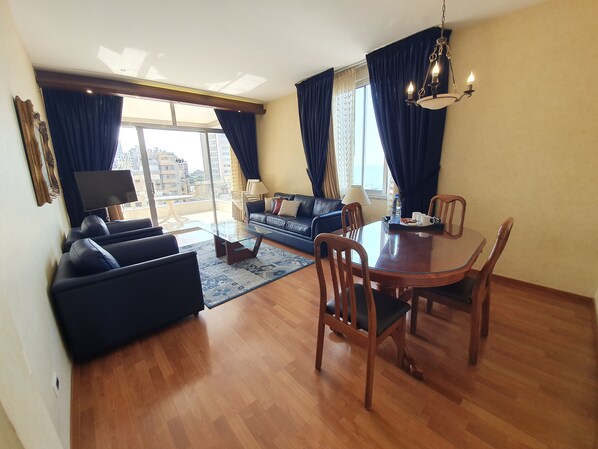A modern living room with a sofa, a glass coffee table, and a dining table with chairs. - Holiday Home Suites (Beirut)