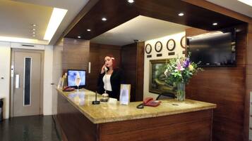 Un mostrador de recepción con un televisor de pantalla plana, un teléfono y un florero con flores.