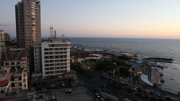 Paisatge urbà costaner amb edificis alts, un port esportiu i una passeig marítim.