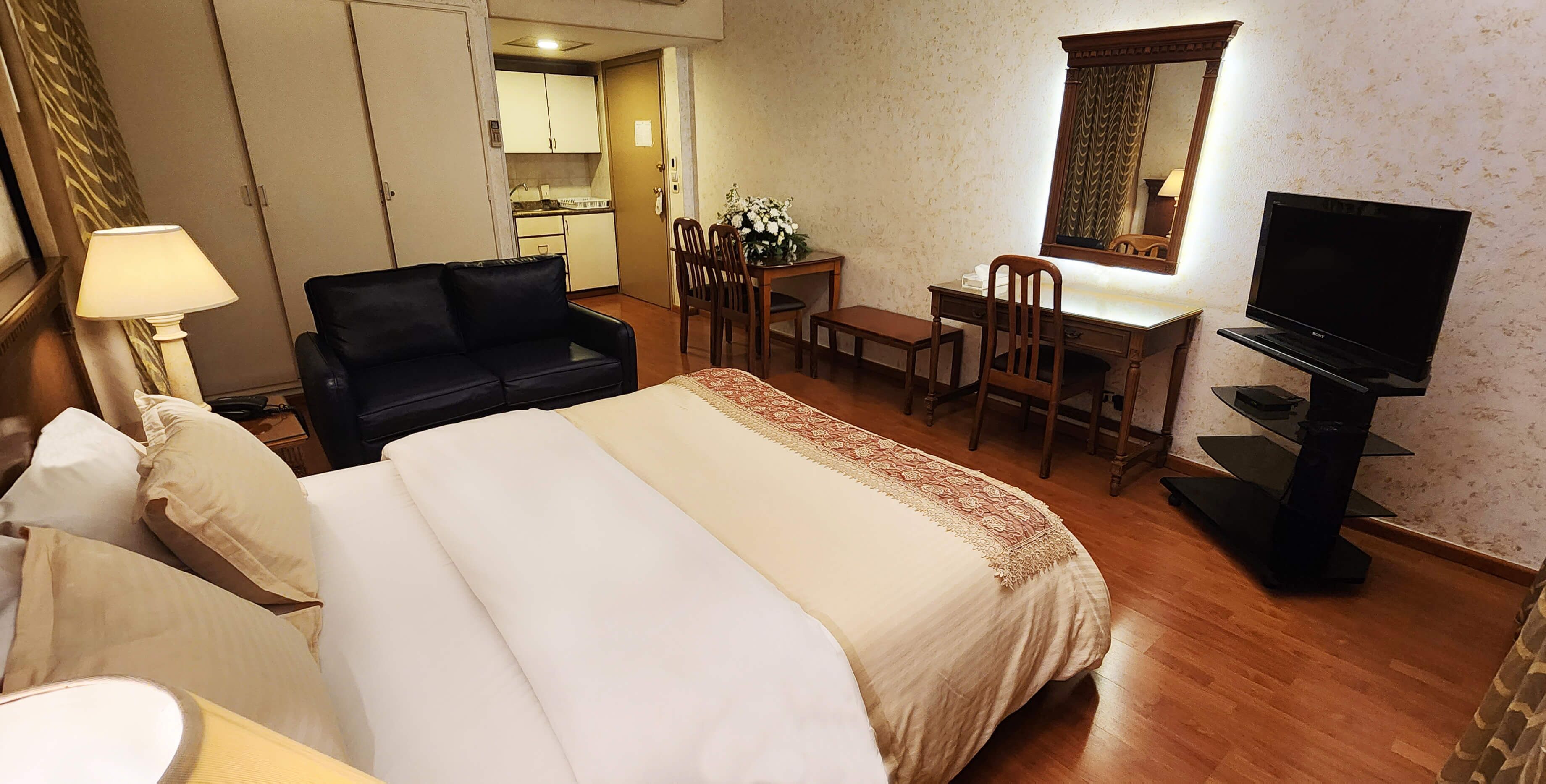 Een hotelkamer met een bed, een bureau, een televisie en een zithoek.