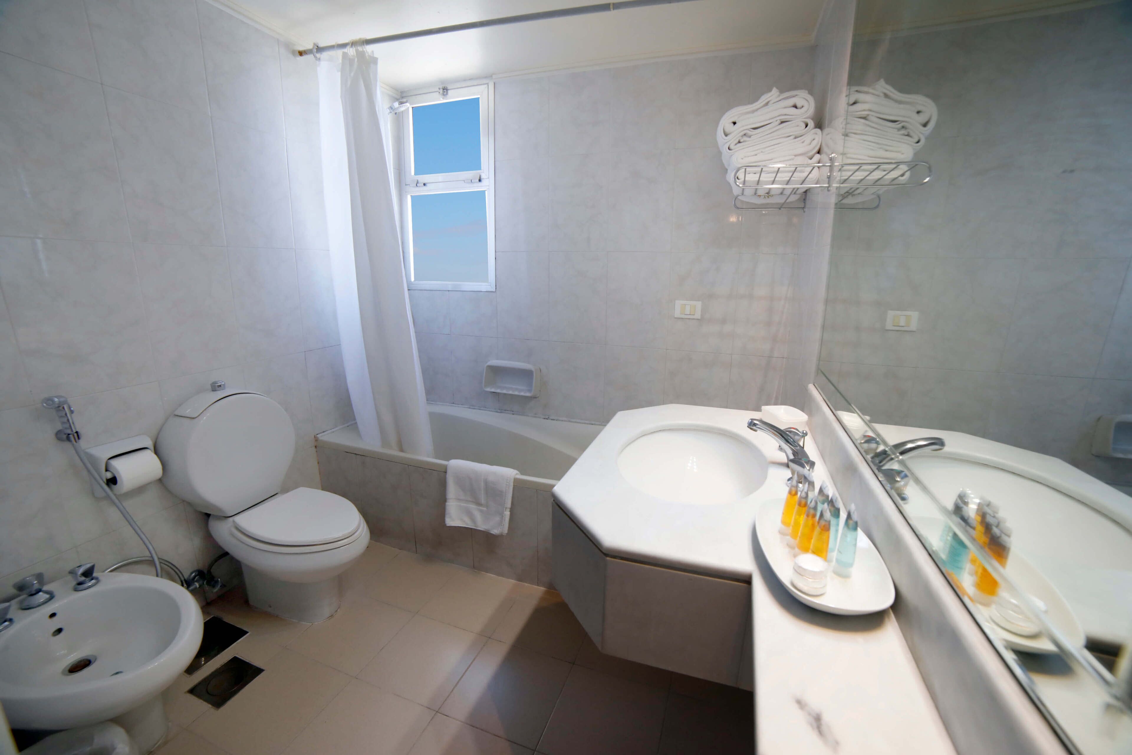 A bathroom with a toilet, bidet, sink, and bathtub.