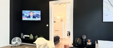 A modern living room with a flat-screen TV mounted on the wall, a white coffee table, and a patterned rug.