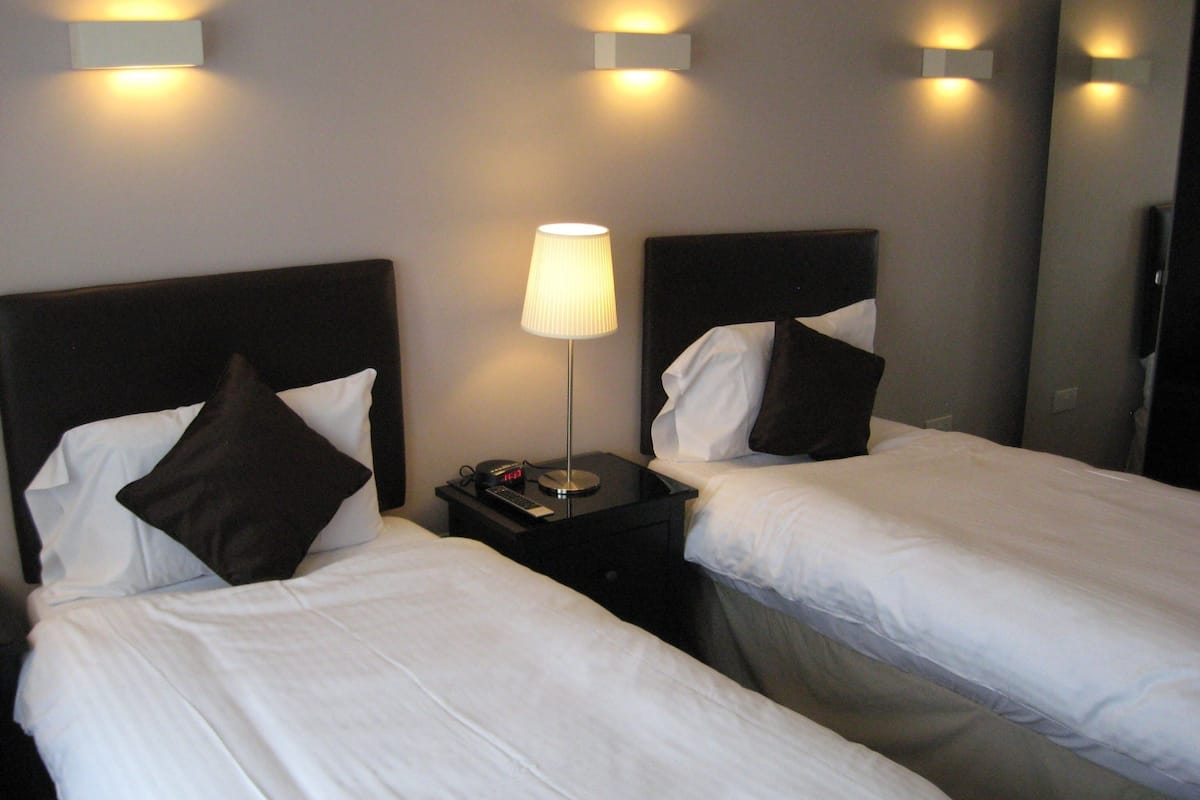 Two single beds with white linens and dark headboards in a hotel room.