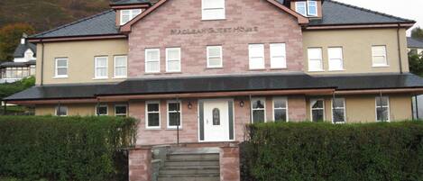 A two-story building with a sign reading "Maclean Guest House."