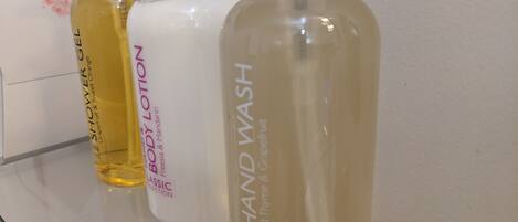 Three bottles of hand wash soap on a reflective surface.