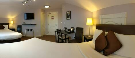 A hotel room with two beds, a desk with a chair, a television, and a lamp.