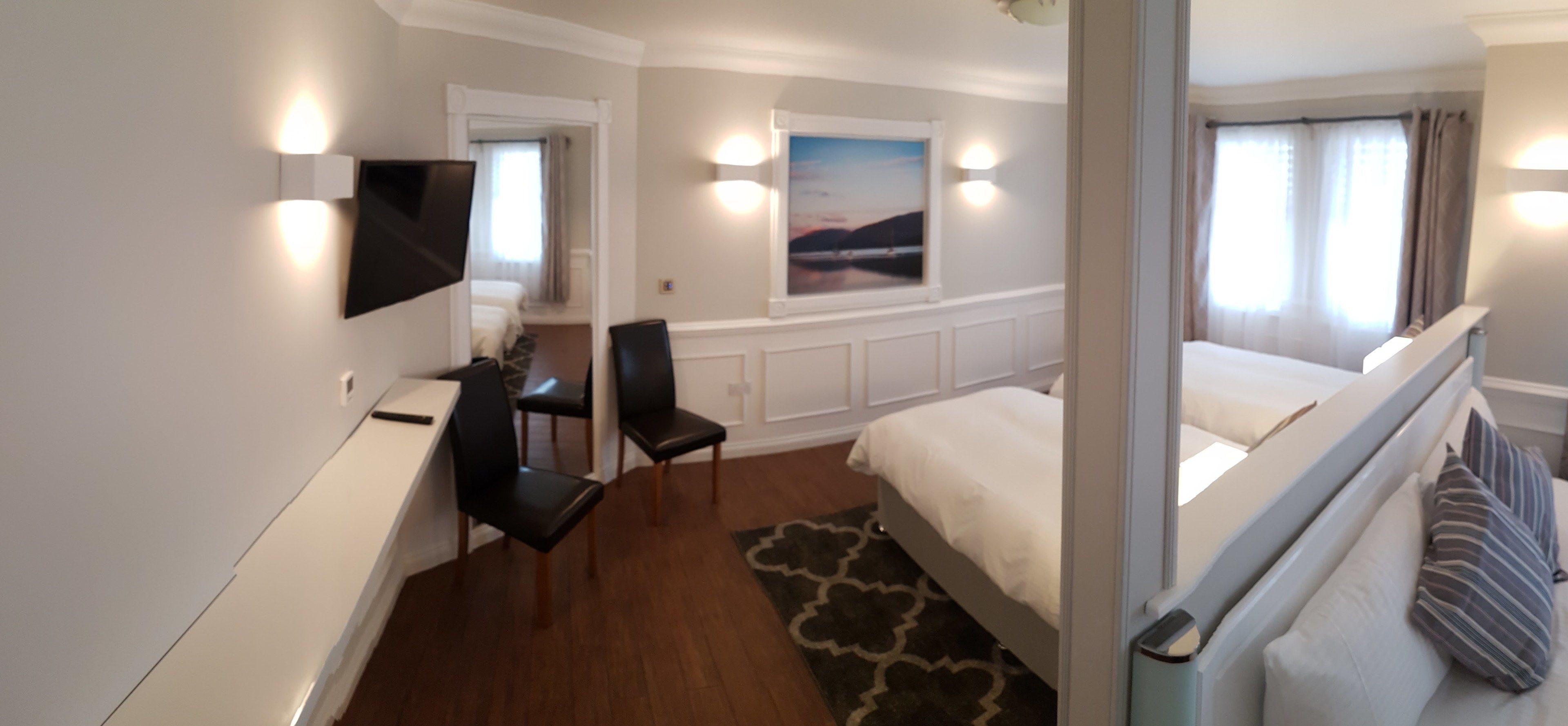 Habitación de hotel con cama, escritorio, silla, televisión y ventana con cortinas.