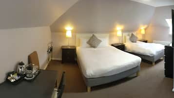 A hotel room with two beds, a desk with a coffee maker, and bedside lamps.