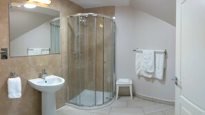 A modern bathroom with a glass-enclosed shower, a sink, and a small vanity.