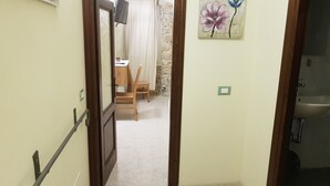 Un pasillo estrecho que conduce a un comedor con una mesa y sillas, una pared de piedra y un cuadro colgado.