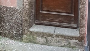 Una puerta de madera con detalles de metal decorativo, un letrero encima y un escalón que lleva a la entrada.