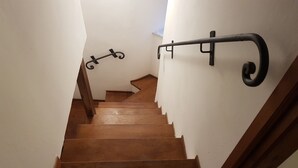 Una escalera de madera con barandilla a la derecha y una barandilla metálica decorativa a la izquierda.