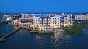 Ein Hotel direkt am Wasser mit mehreren Etagen, einem Steg und einem Poolbereich.