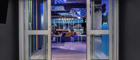 A modern interior with a glass door leading to a seating area with sofas and tables.