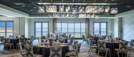 A conference room with round tables, chairs, and hanging light fixtures.