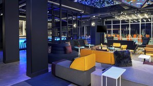 Ein moderner Lounge-Bereich mit Sitzgelegenheiten, Blick auf den Pool und stimmungsvoller Beleuchtung.