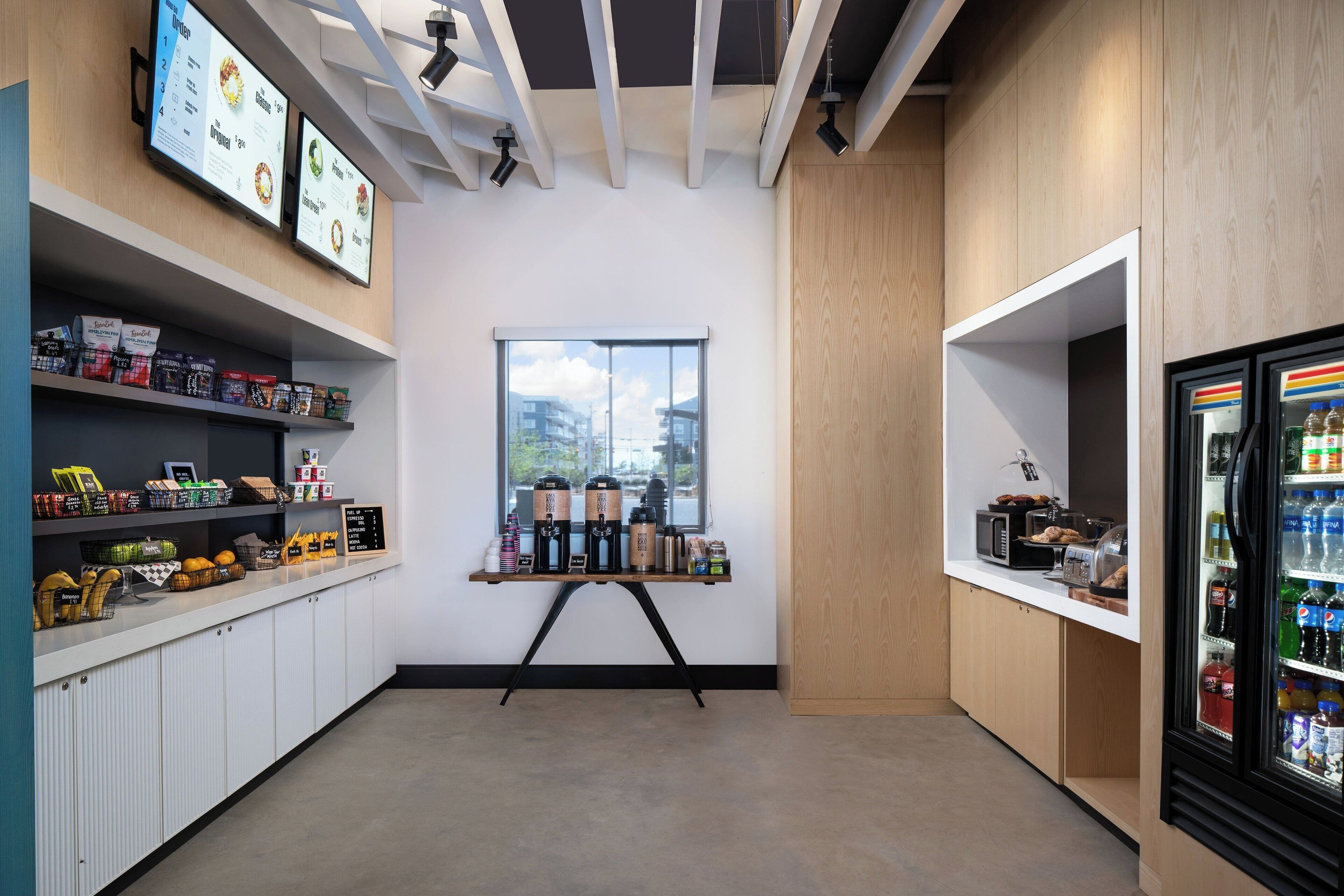 A modern kitchen with a coffee station, a refrigerator, and a window with a view.